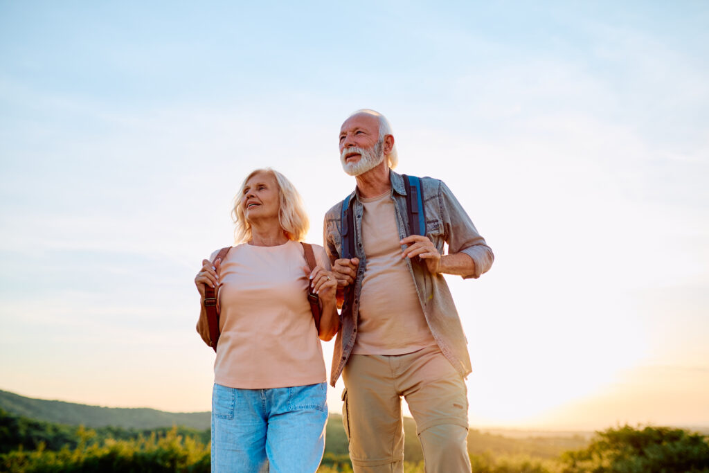 Senior couple walking outdoors with backpacks, enjoying a healthy active lifestyle and freedom during retirement